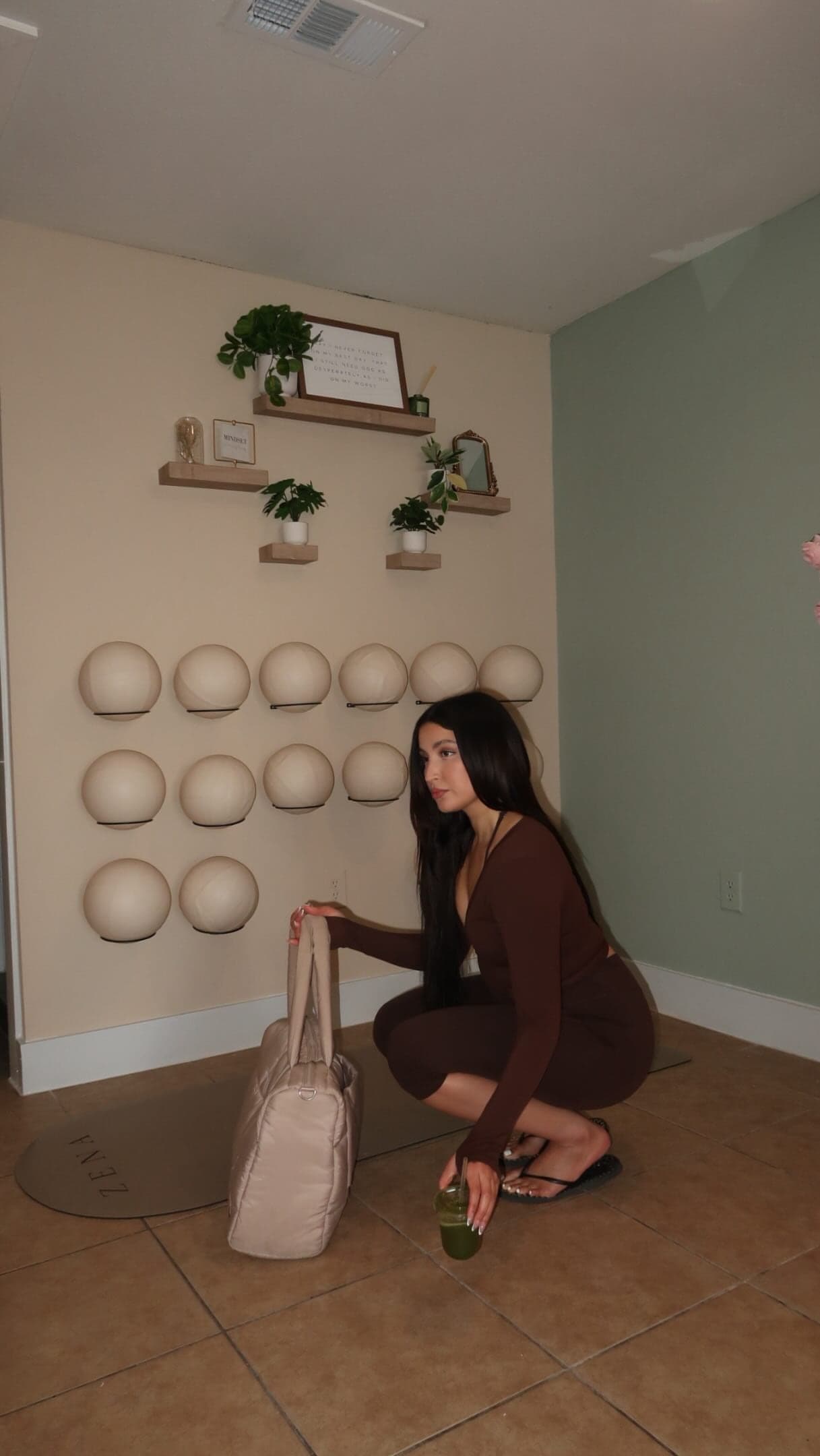 The Zena Pilates studio: a wall of Pilates balls, floating shelves with plants and a sage accent wall