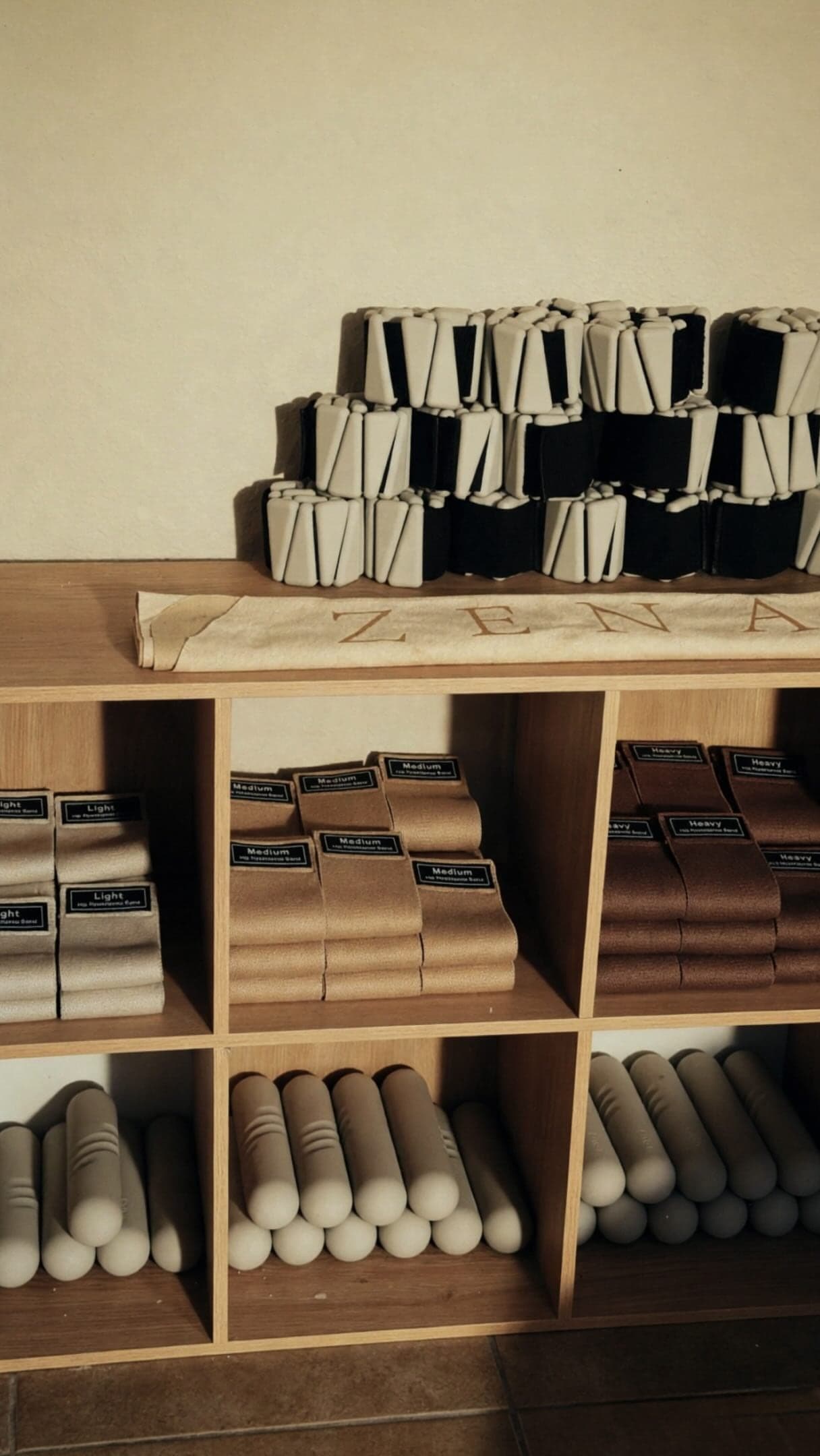 Wooden cubbies stocked with rolled mats, foam rollers and folded Zena towels